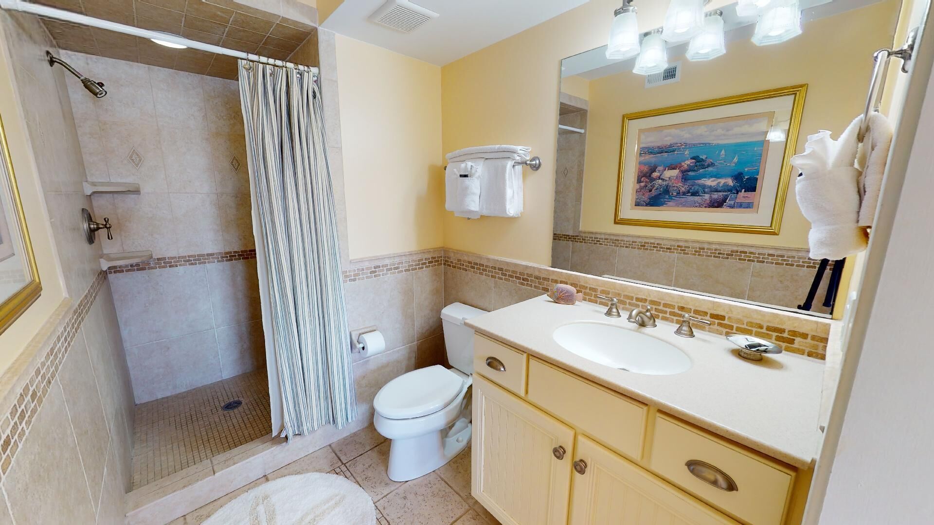 Een badkamer met douche, toilet, wastafel en een grote spiegel met een lijst eromheen.