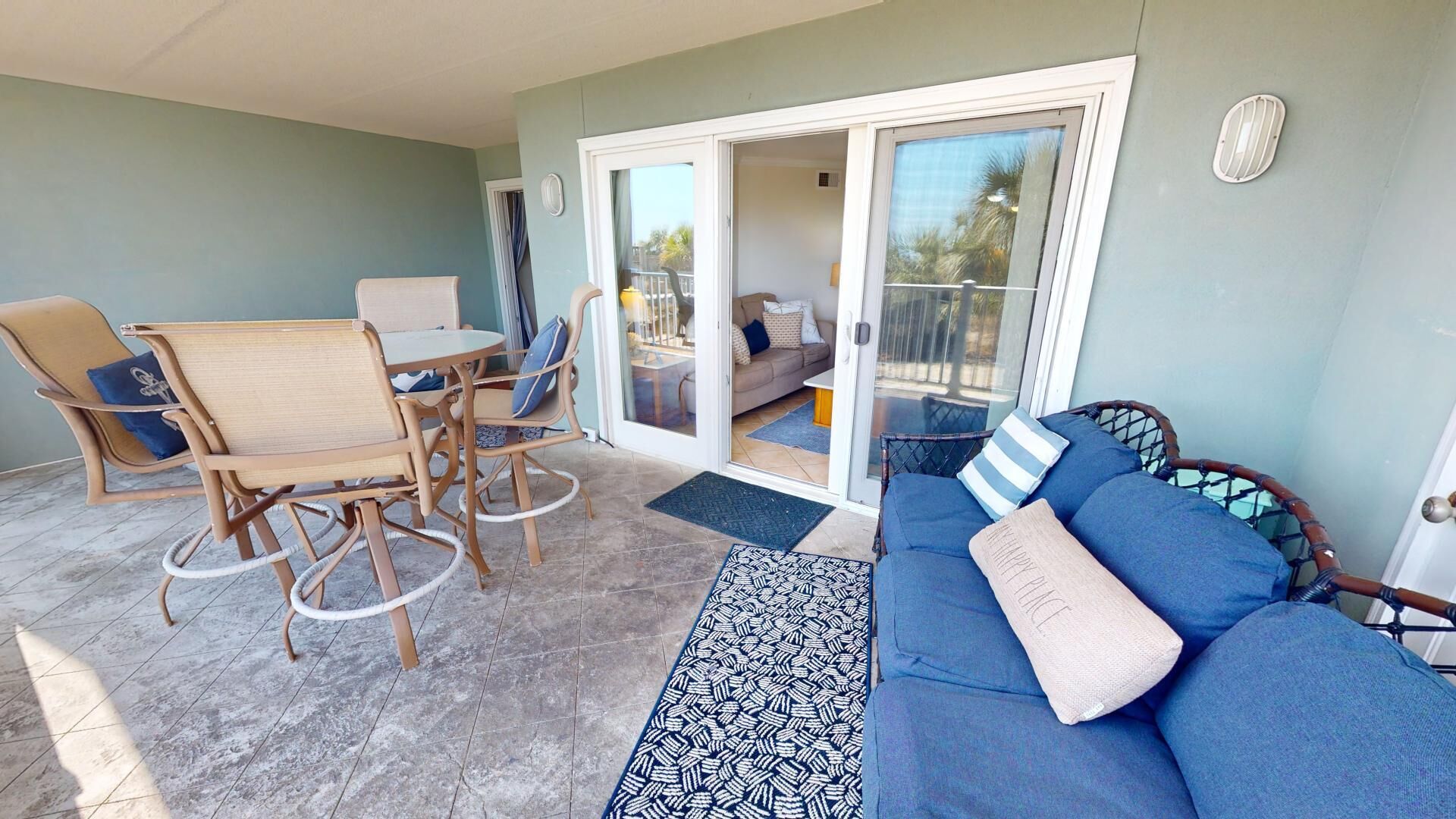A sunlit patio area with a dining set, a sofa, and a view into the living room.