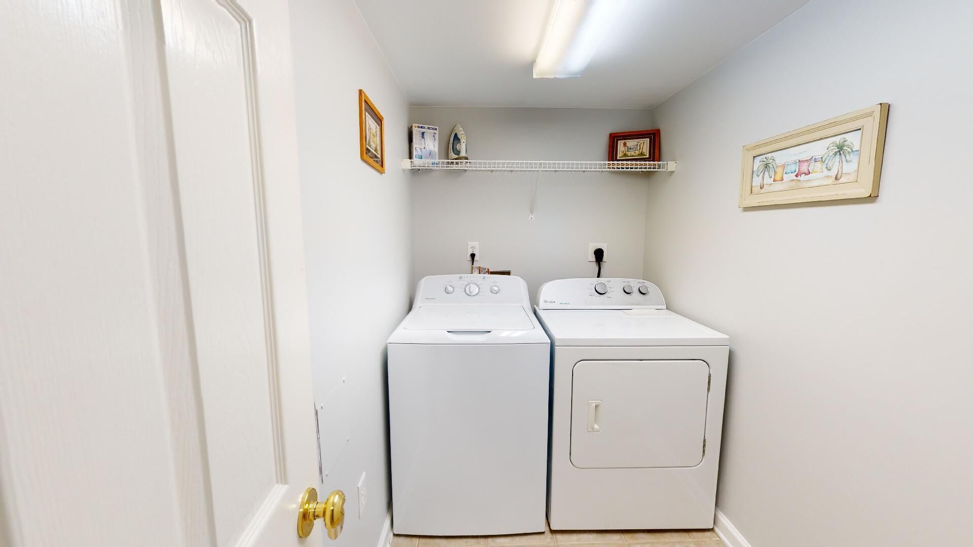 A laundry room with two white washing machines and a shelf above them.