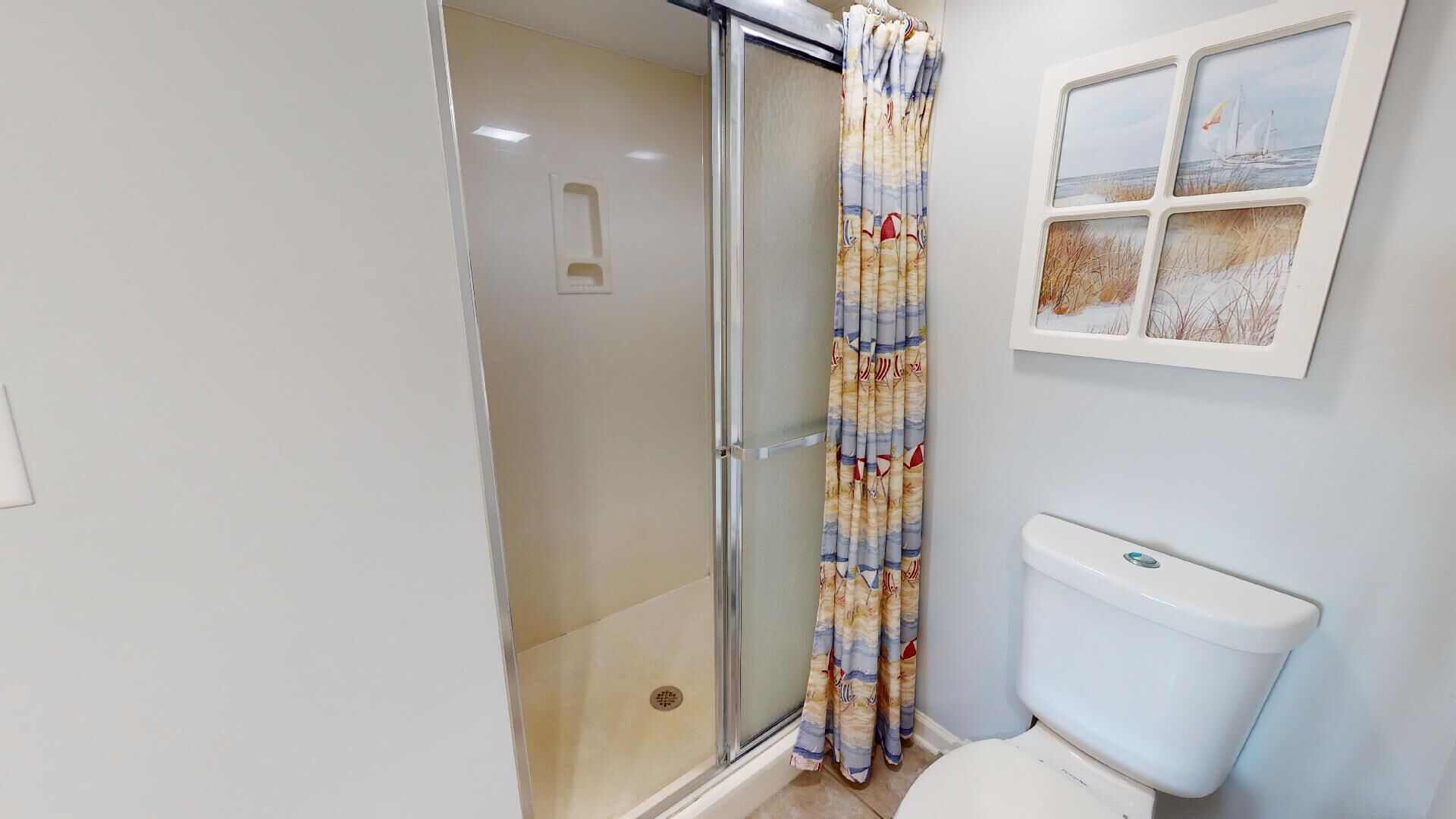 Une salle de bain avec une douche à parois de verre, des toilettes et un cadre photo fixé au mur.