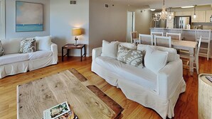 A living room with a sofa, a coffee table, and a dining area with chairs and a table. - Fort Screven Villas Tybee Vacation Rentals (Tybee Island)