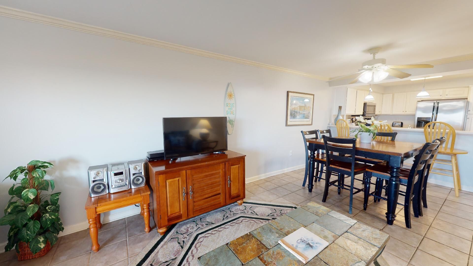 A living room with a TV, speakers, and a dining area with chairs and a table.