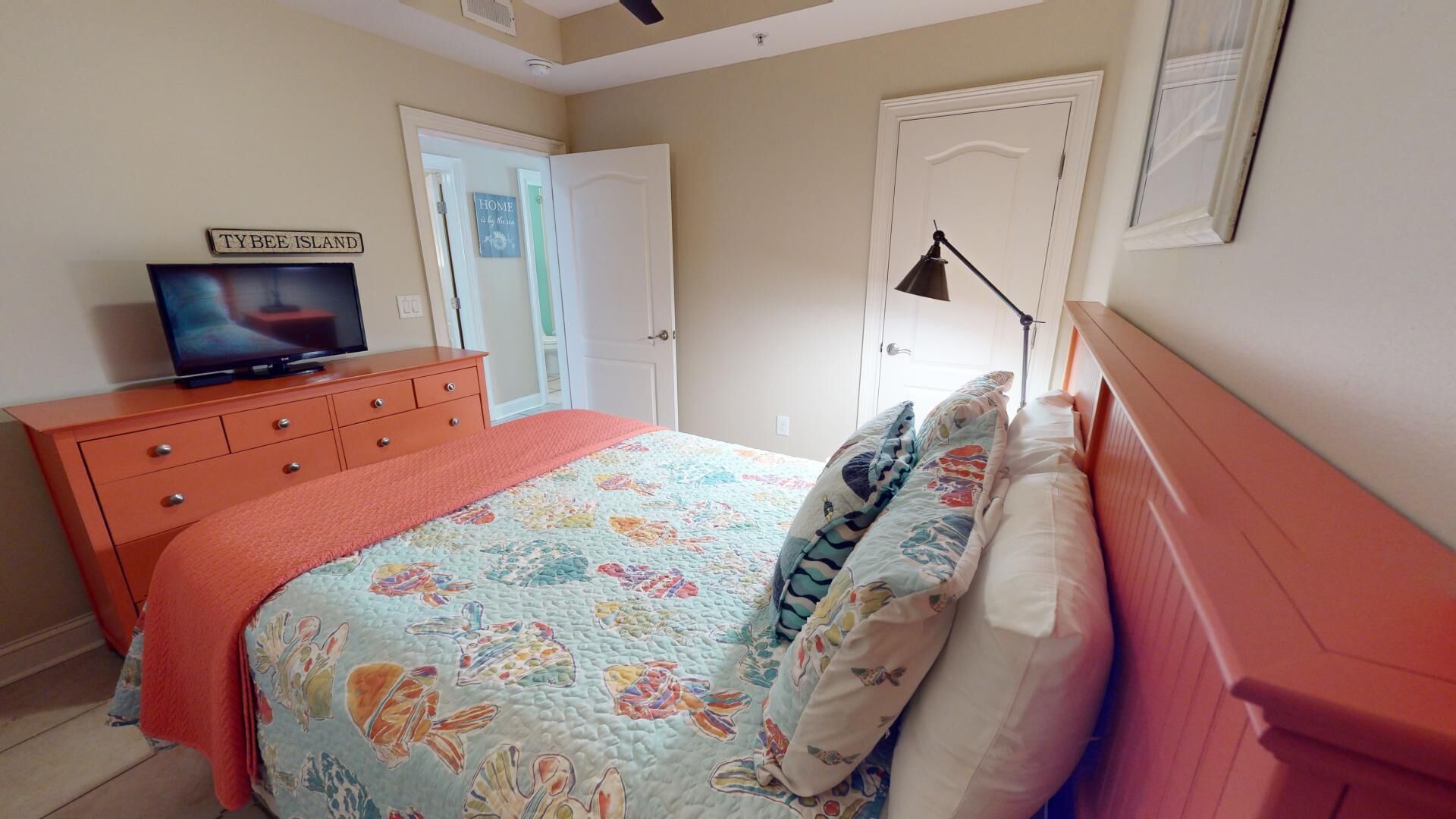 Una camera da letto con un letto, una cassettiera, una televisione e una porta.