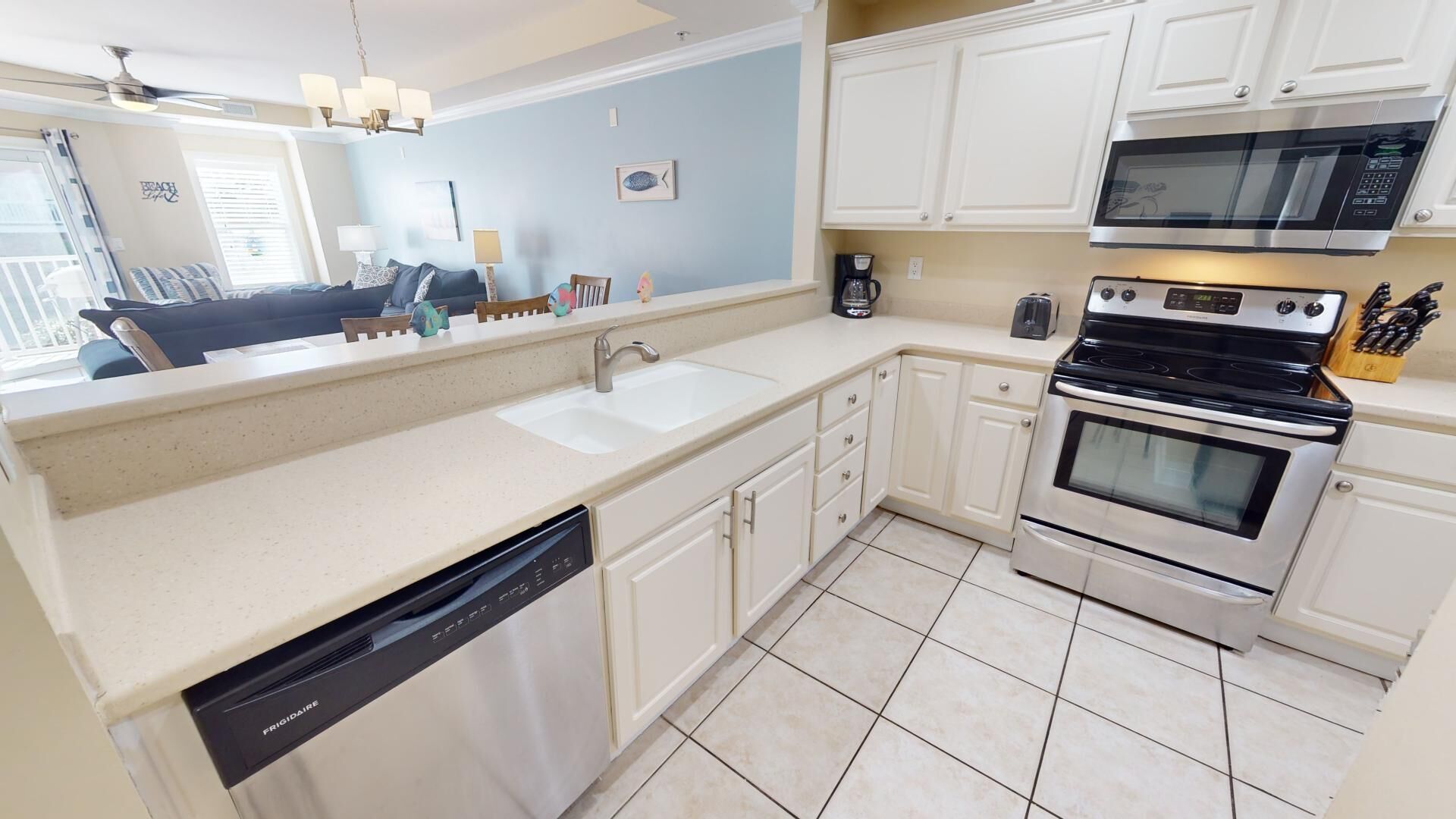A kitchen with a dishwasher, stove, microwave, and a large window.