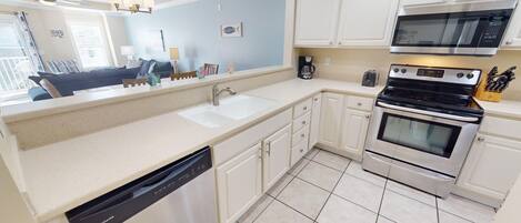 A kitchen with a dishwasher, stove, microwave, and a large window.