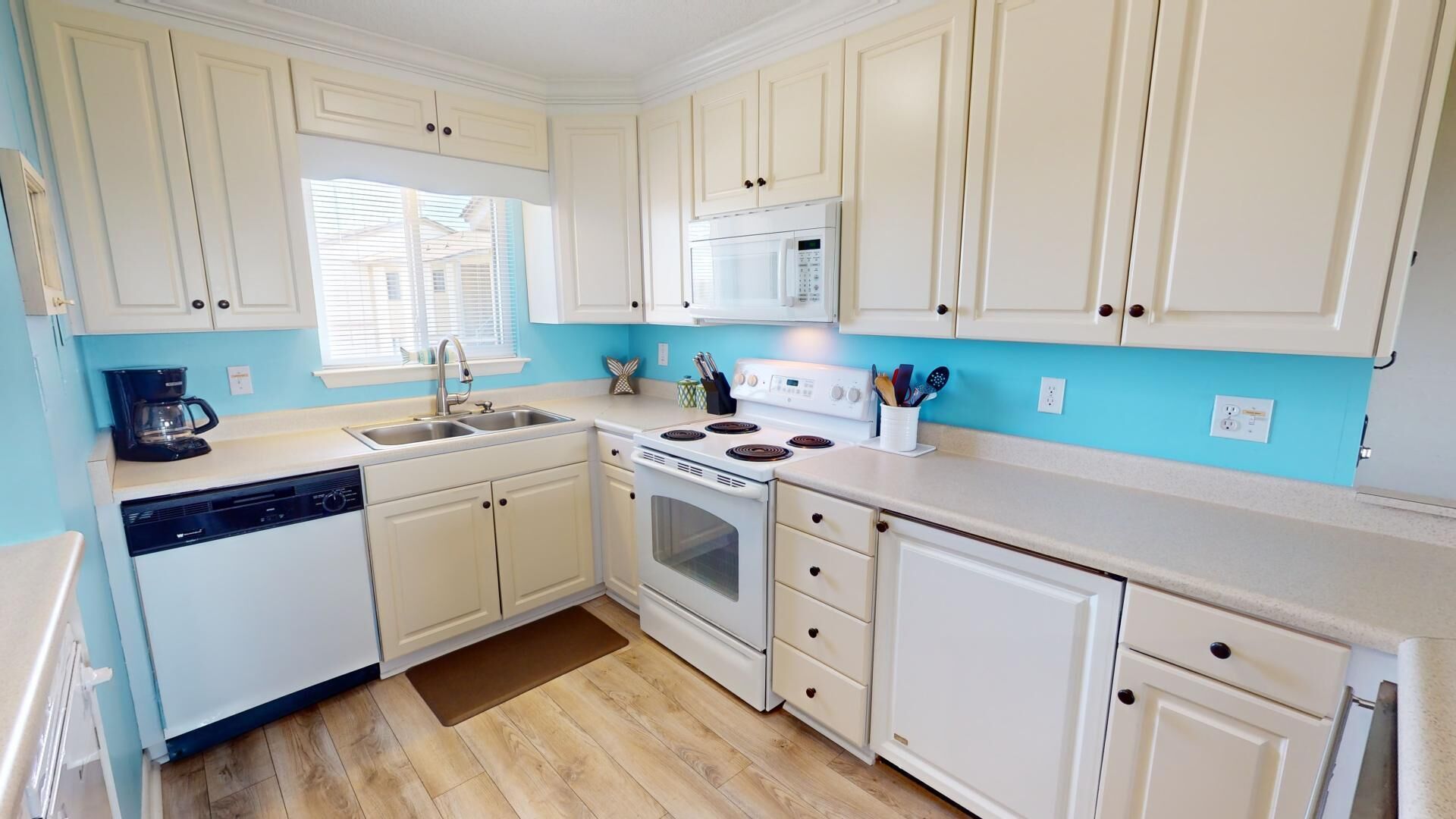 A compact kitchen with white cabinets, a built-in microwave, a stove, and a coffee maker.