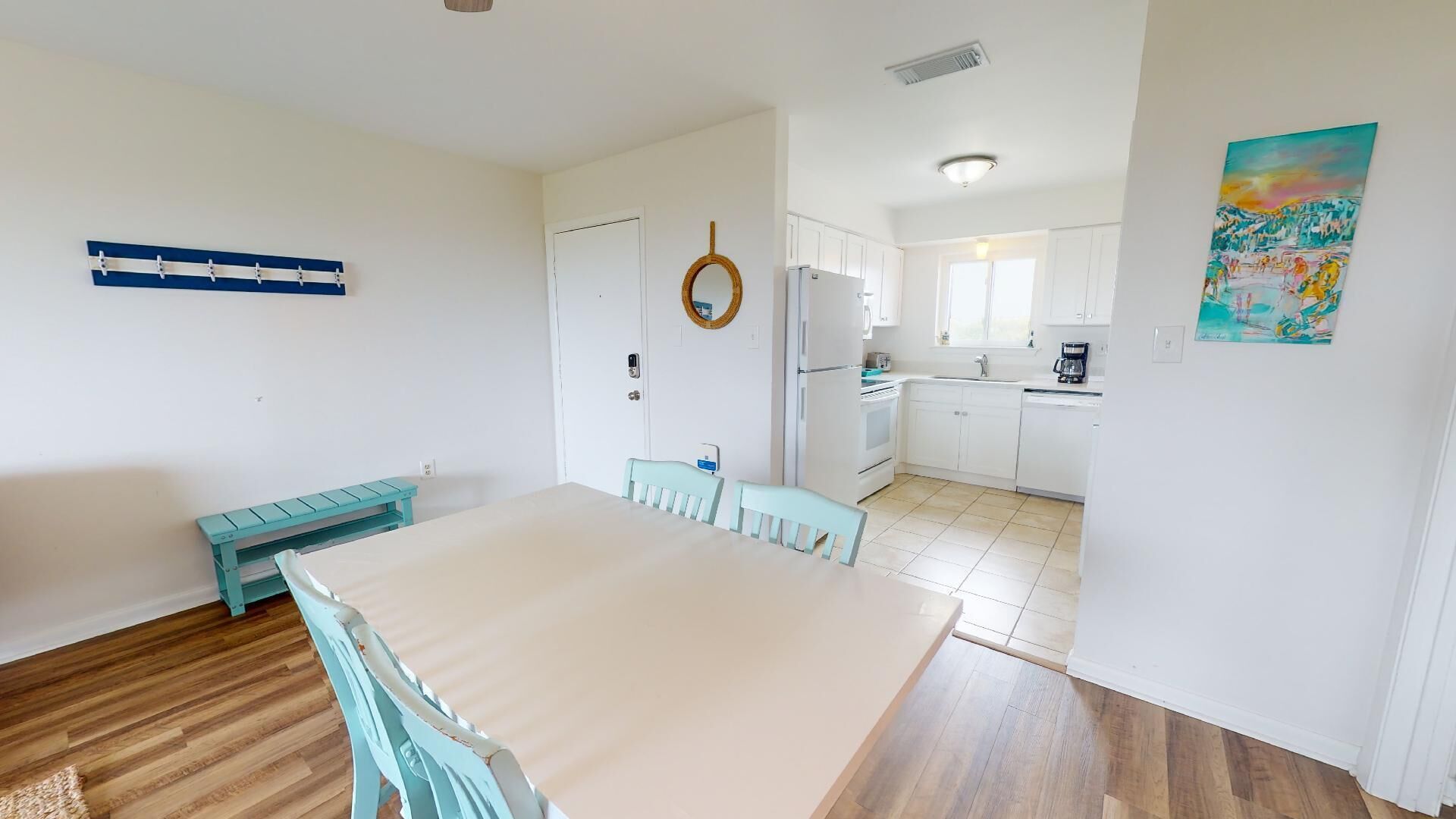 A compact kitchen with white cabinets, a refrigerator, and a coffee maker.
