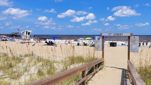 A beach with a wooden walkway leading to a sign reading "17th Street". Beach umbrellas and chairs are visible, and the ocean is in the background. - Oceanview A by Tybee Vacation Rentals (Tybee Island)