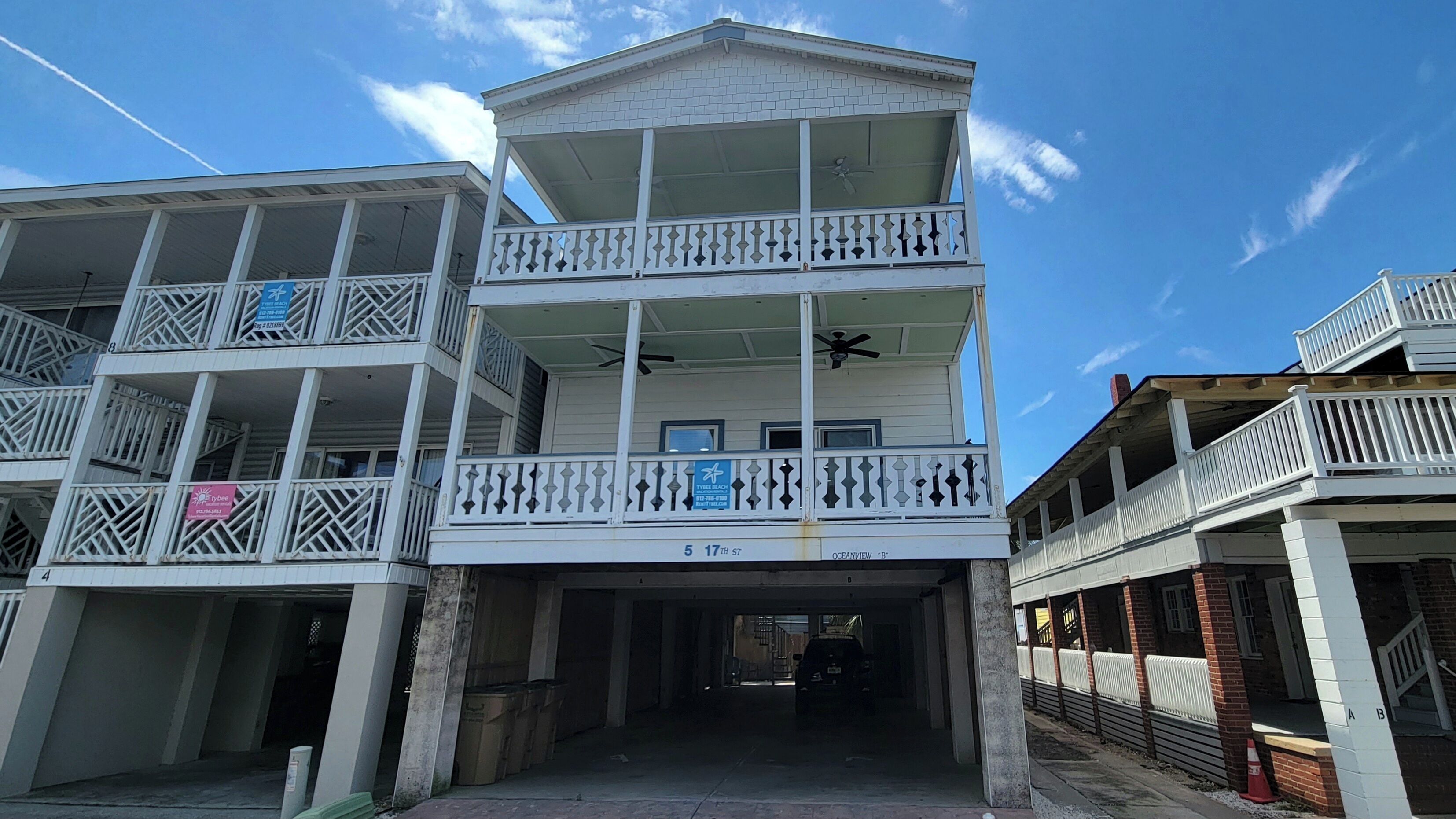 A multi-story building with balconies, a covered entrance, and a sign indicating 'Tybee Beach'.