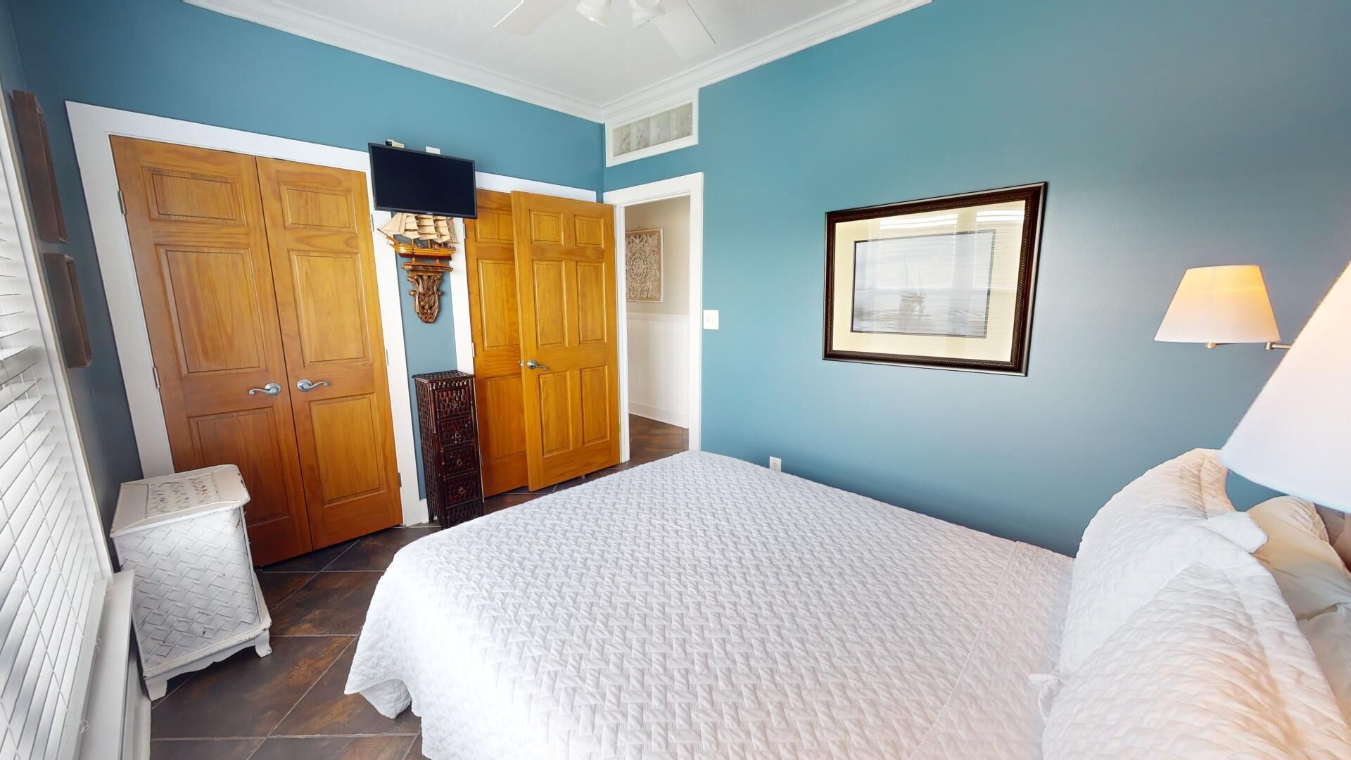 A bedroom with a large bed, wooden wardrobe, and a framed picture on the wall.