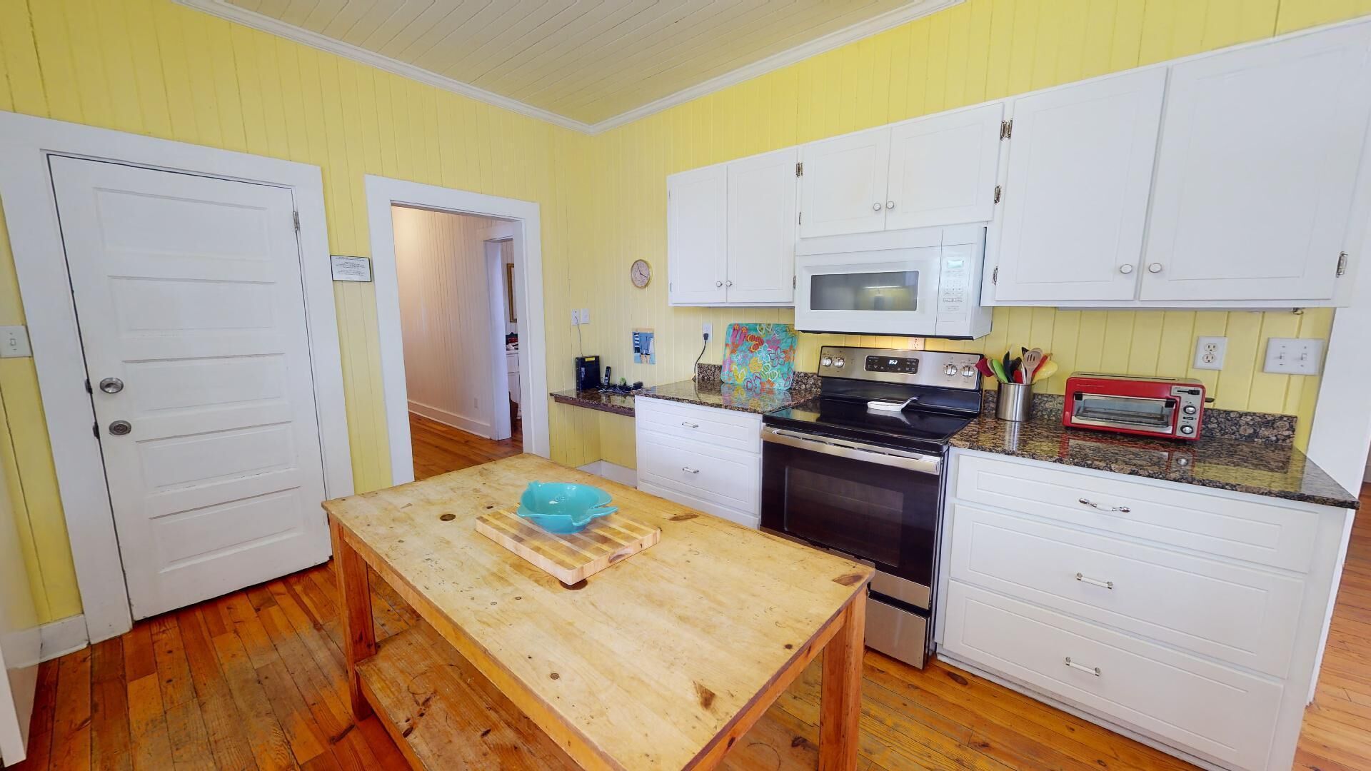 A compact kitchen with white cabinets, a microwave, a stove, and a toaster.