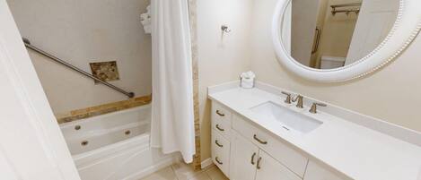 A bathroom with a bathtub, a shower, a sink with a mirror, and a toilet.