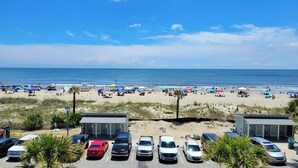 A beach with a parking lot and beach umbrellas. - Pelican Point by Tybee Vacation Rentals (Tybee Island)