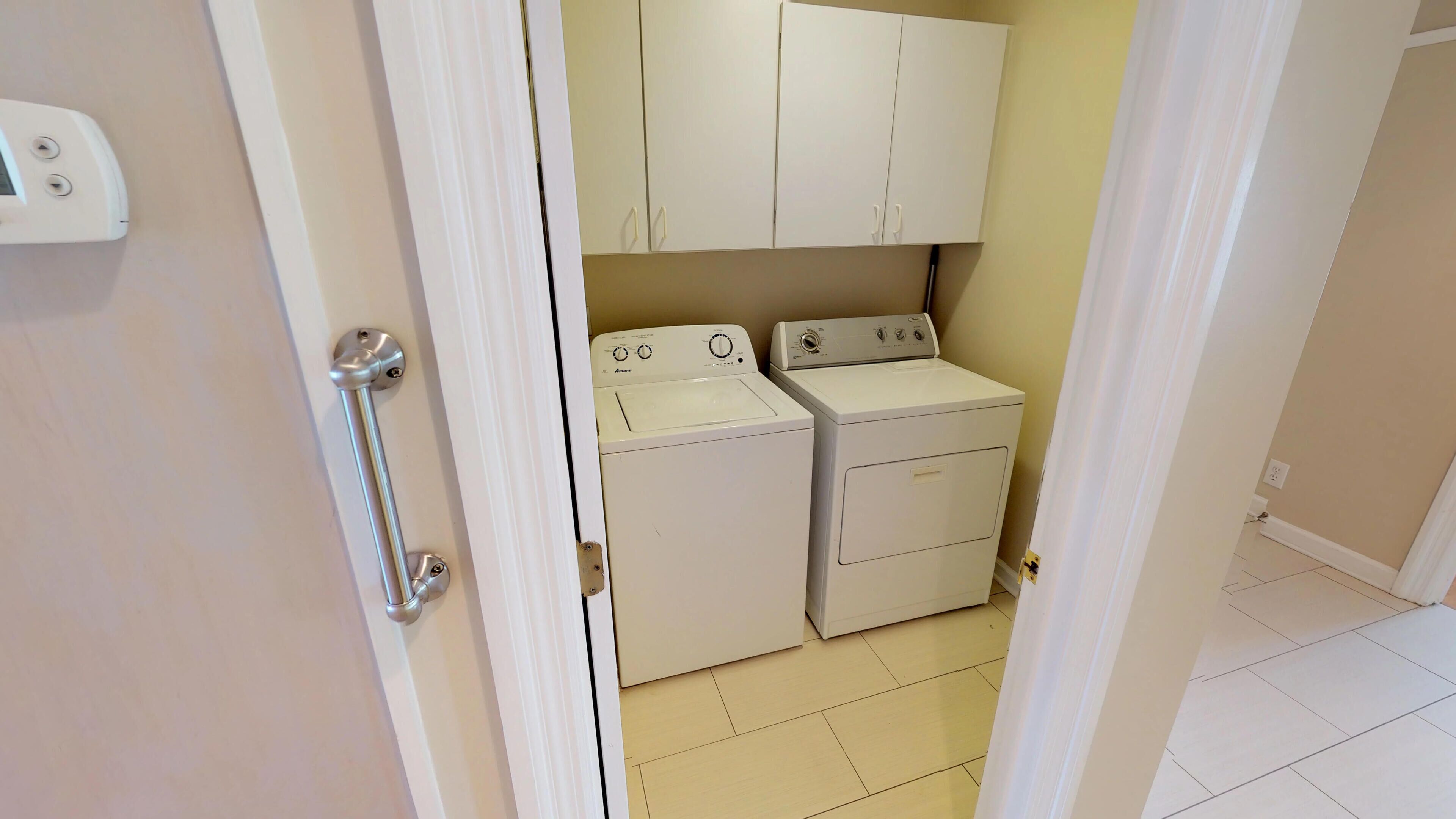 A laundry room with two white washing machines and a cabinet above them.