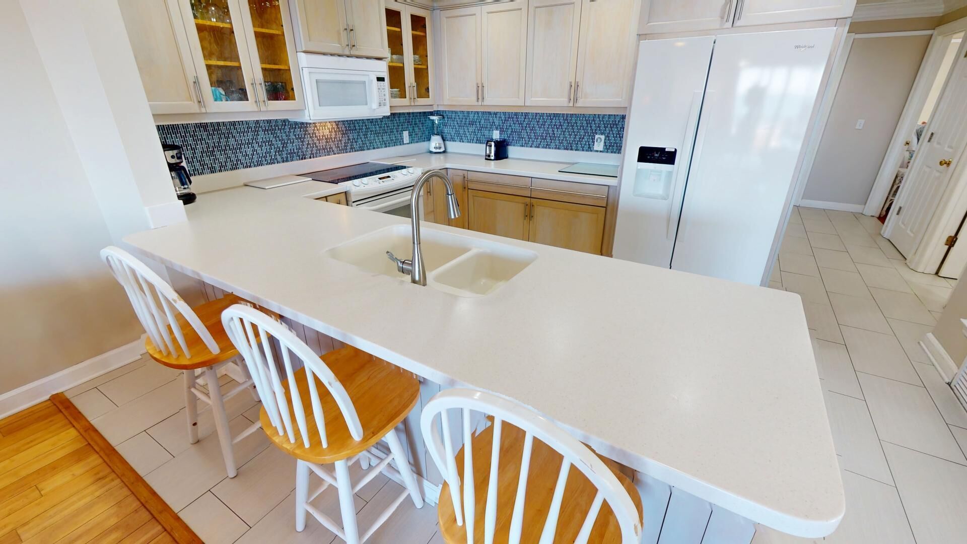 A modern kitchen with a white countertop, two wooden chairs, and a built-in sink.