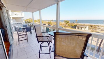 A balcony with a view of the beach and ocean.