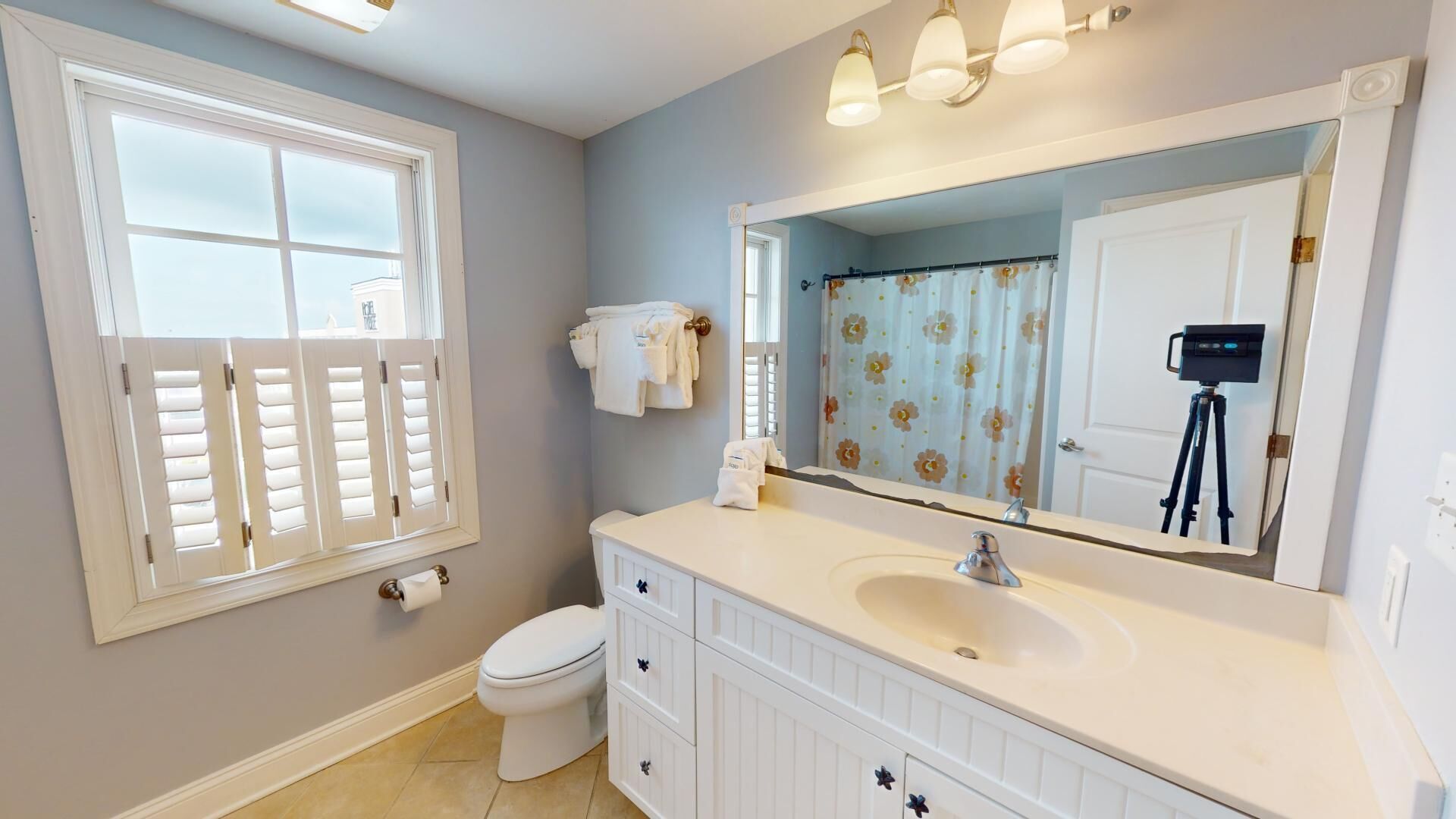 A bathroom with a toilet, sink, vanity, and a large mirror.