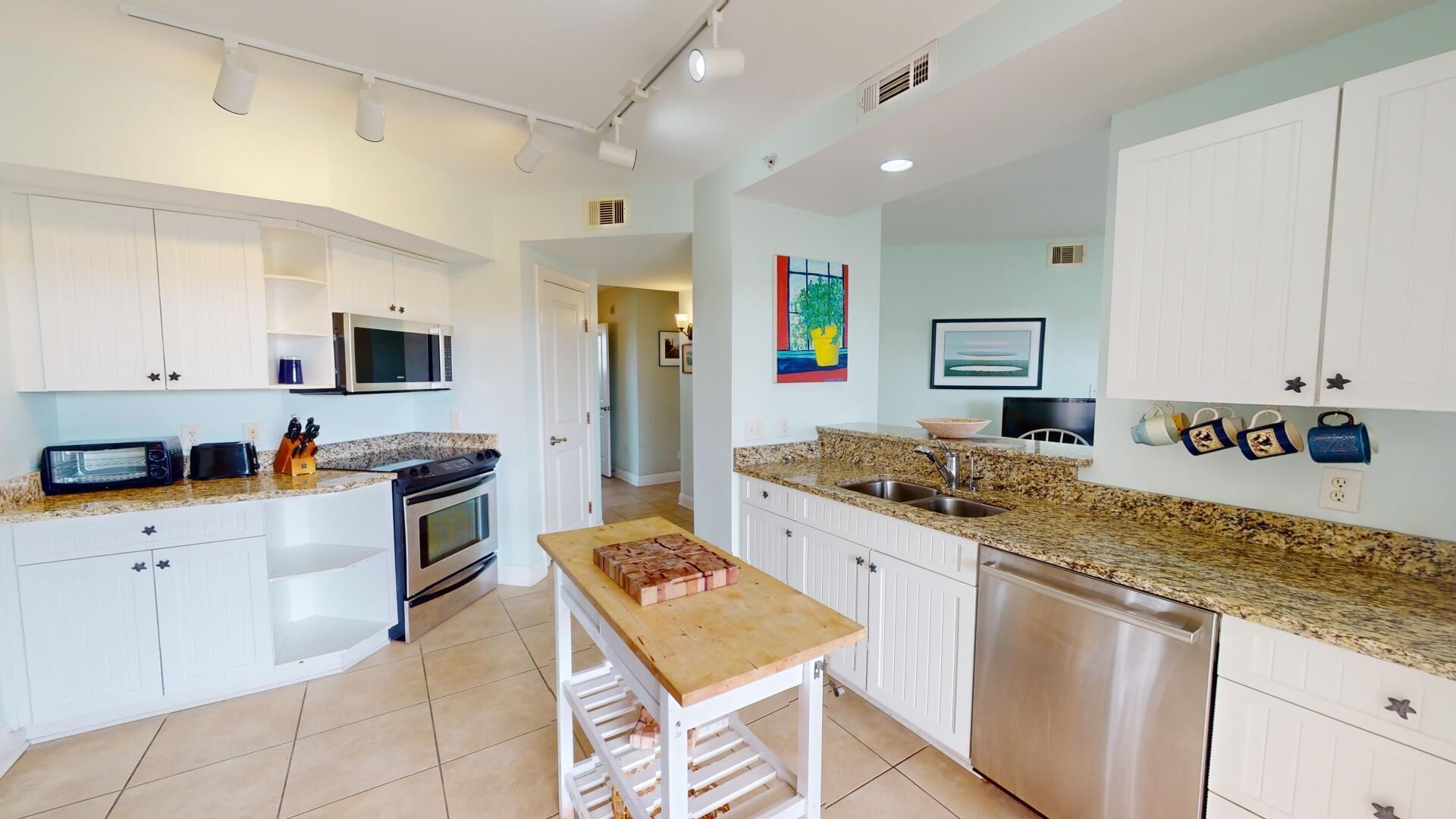 A modern kitchen with white cabinets, a granite countertop, a built-in oven, and a stainless steel dishwasher.