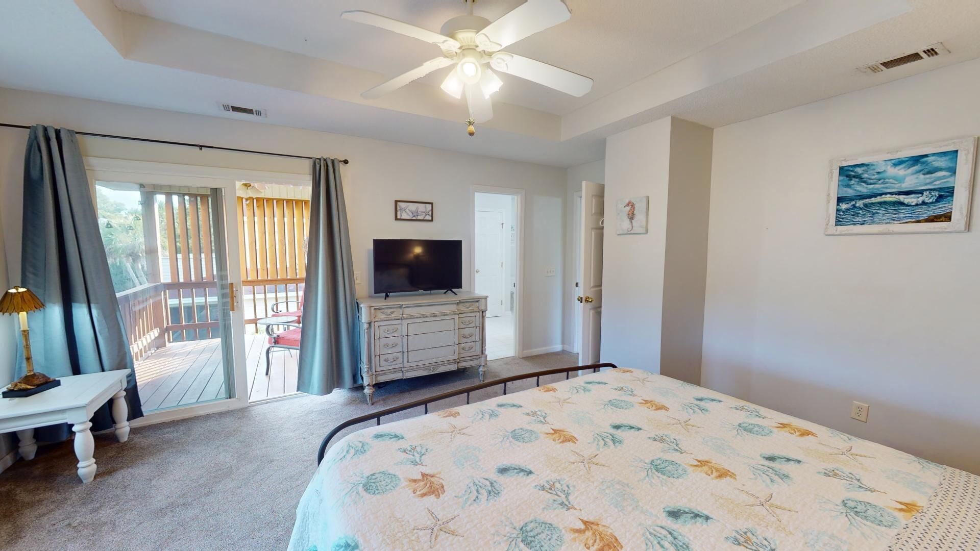 A bedroom with a bed, a TV, a desk, and a balcony.