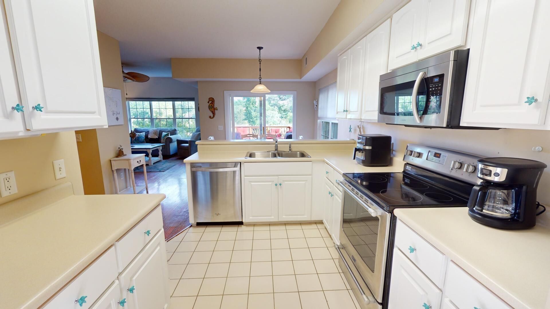 A kitchen with white cabinets, a stainless steel dishwasher, a black stove, and a microwave.