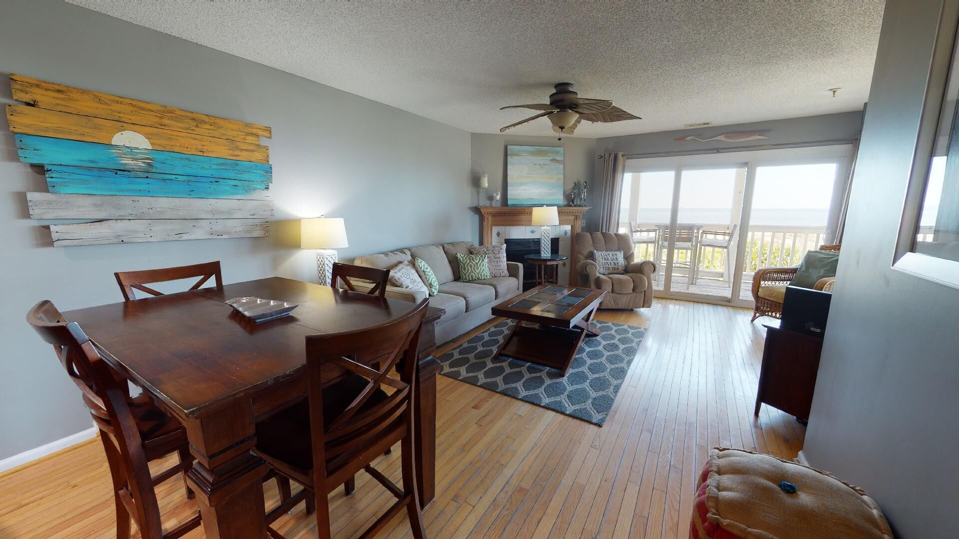 A spacious living area with a wooden dining table, a sofa, and a fireplace.