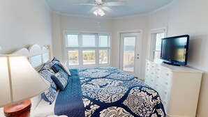 A bedroom with a large bed, a television, and a ceiling fan.