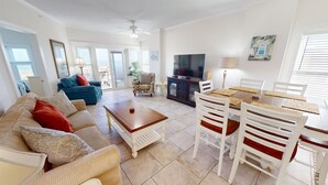 A spacious living room with a sofa, coffee table, TV, and dining area with chairs and a table.
