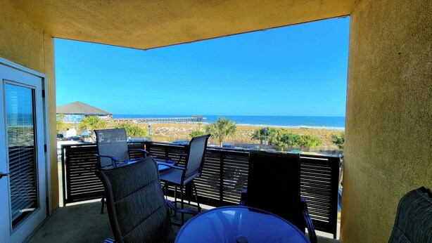 A balcony with a view of the beach and ocean.