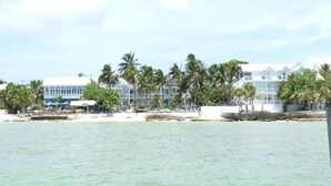 Hotel na praia com vários edifícios, palmeiras e vista clara do oceano.