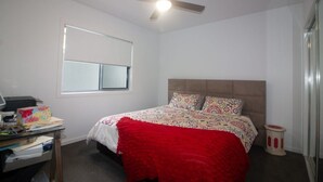 A bedroom with a bed, a desk with a computer, a window, and a ceiling fan. - Azure on Bondi Place (Tweed)