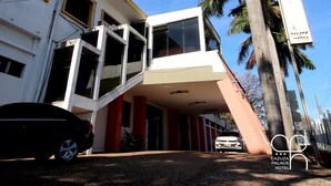 Un hotel de diseño moderno, con una escalera destacada que lleva a la entrada, una palmera en primer plano y un cielo azul despejado.