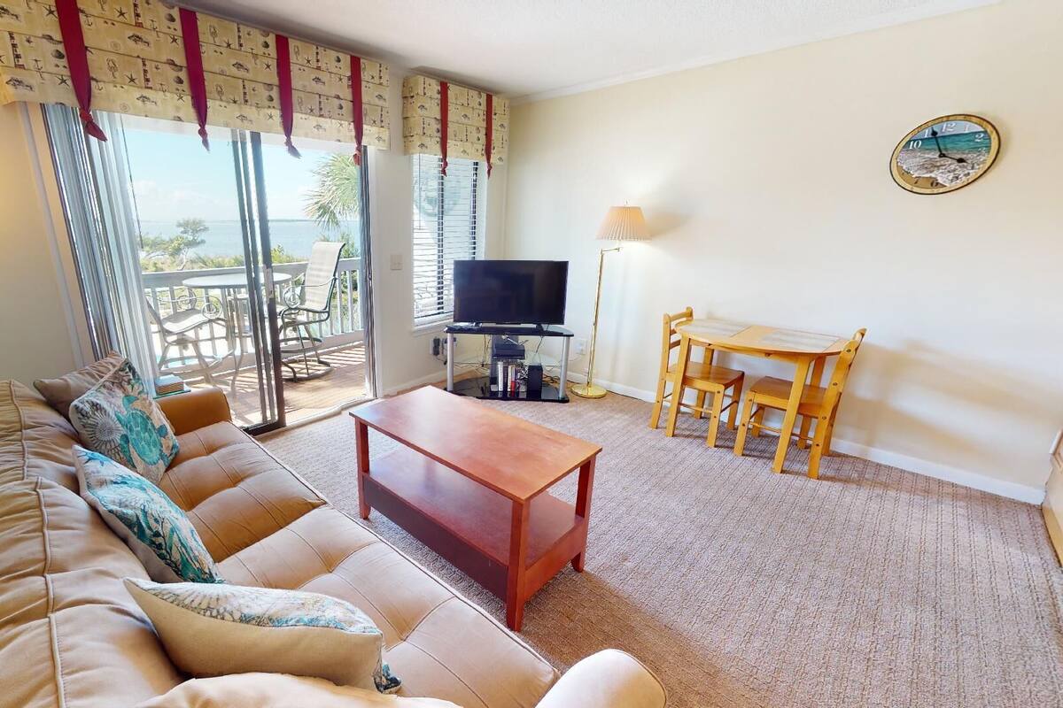 A living room with a sofa, a coffee table, a TV, and a dining area with chairs.