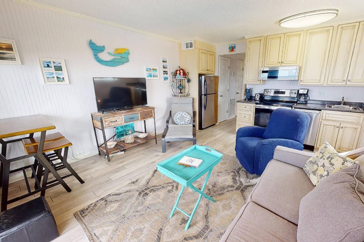 A compact living space with a kitchenette, a dining area, and a seating area with a sofa and armchair.