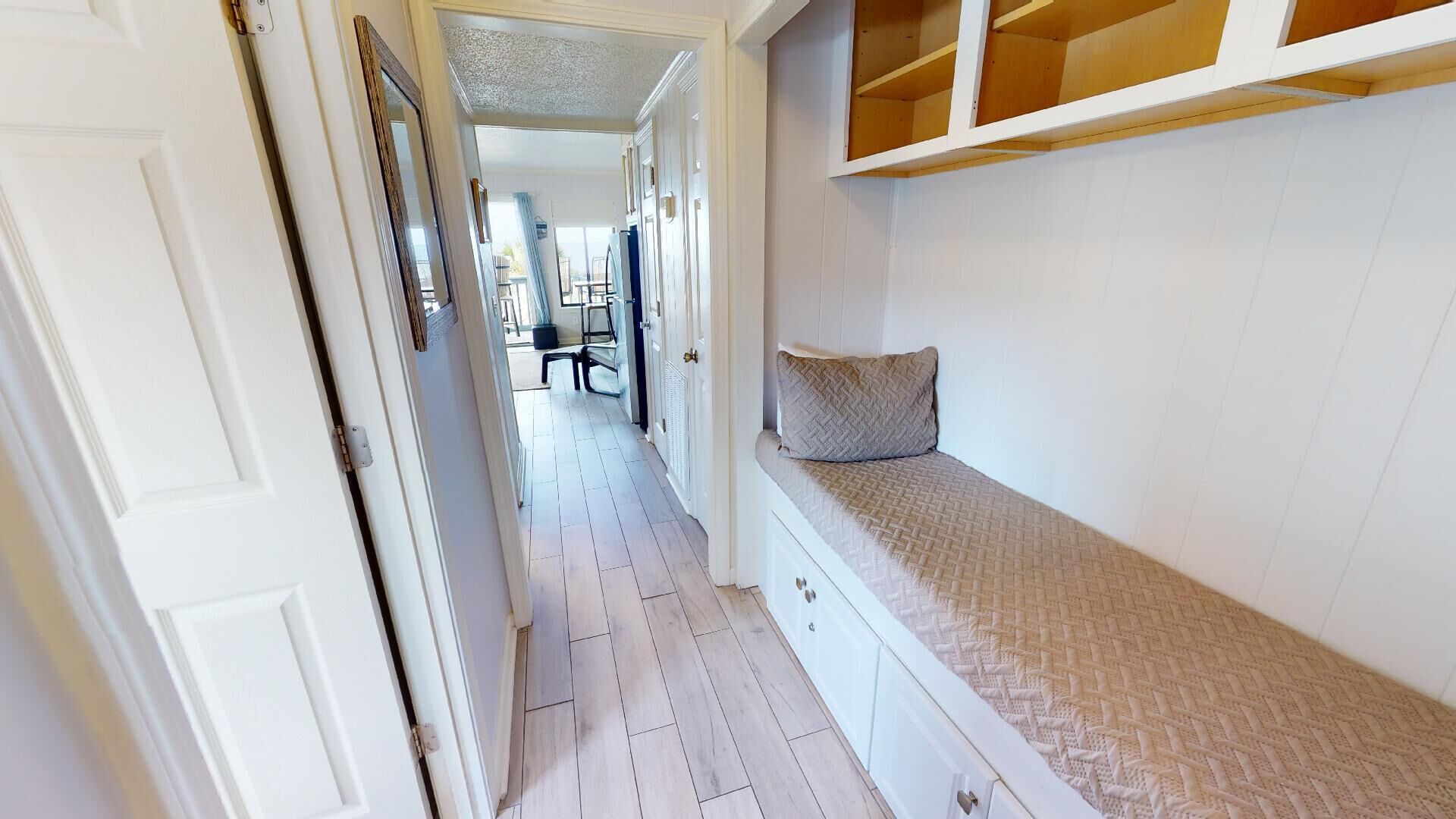A narrow hallway with a bench and a door on the left.