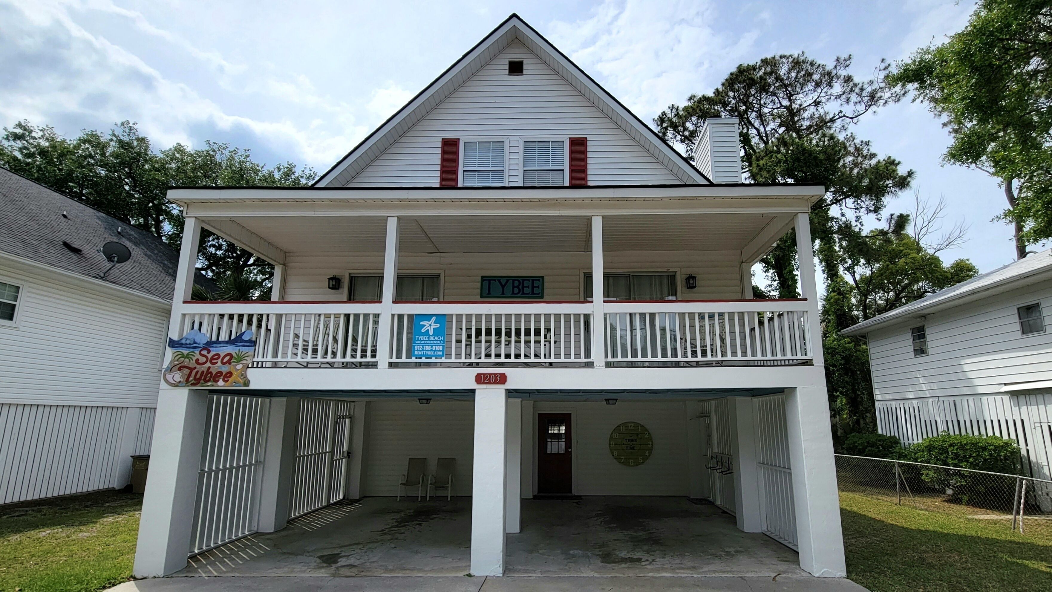 Un edificio a due piani con un balcone, un cartello con la scritta 'Sea Tybee' e una cassetta delle lettere.