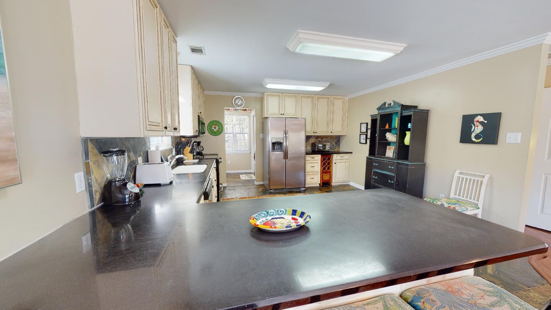 A kitchen with a central island, a refrigerator, and a microwave.