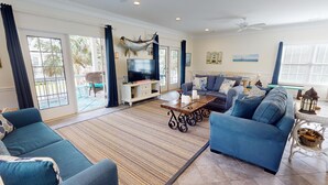 A spacious living room with a large TV, comfortable seating, and a view of the outdoors. - Serendipity by Tybee Vacation Rentals (Tybee Island)