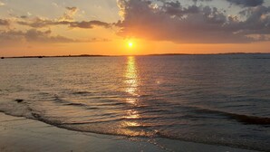 A sunset over a calm sea with a distant shoreline. - Serendipity by Tybee Vacation Rentals (Tybee Island)