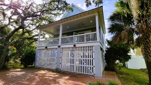 A two-story building with a balcony, a gated entrance, and a brick pathway leading to it. - Serendipity by Tybee Vacation Rentals (Tybee Island)