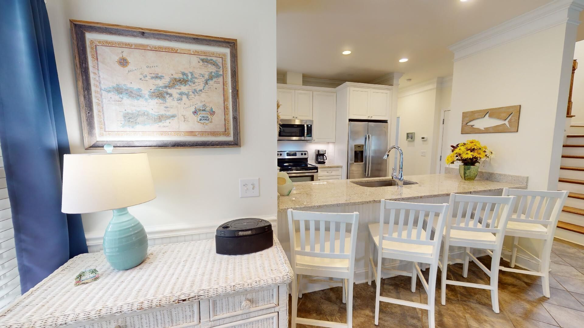 A modern kitchen with white cabinetry, stainless steel appliances, and a central island with bar stools.