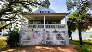 A two-story building with a balcony, a gated entrance, and a brick pathway leading to it. - Serendipity by Tybee Vacation Rentals (Tybee Island)