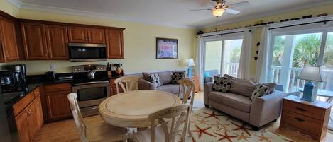 A cozy living room with a dining table, a sofa, and a ceiling fan.