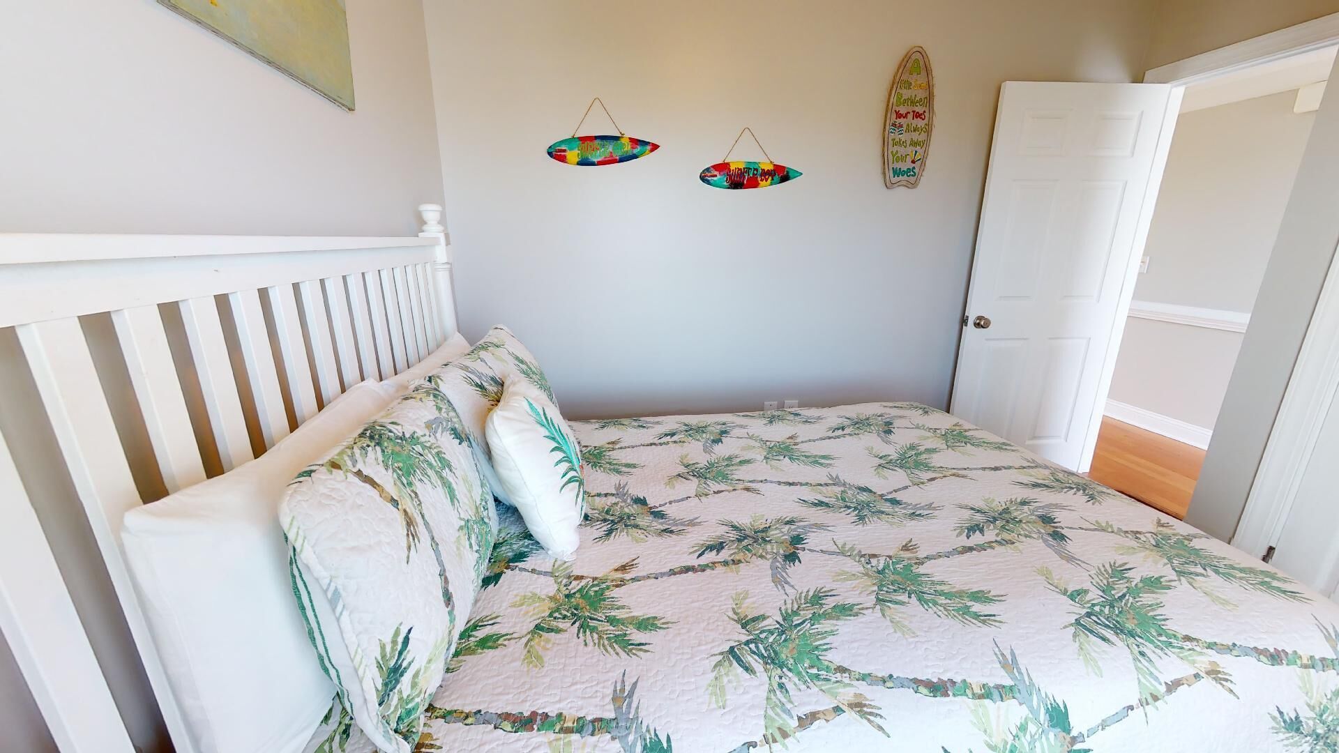A bedroom with a bed, white headboard, and a door to the right.