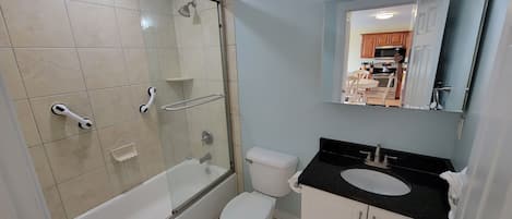 Un baño con bañera, inodoro y lavamanos con espejo.