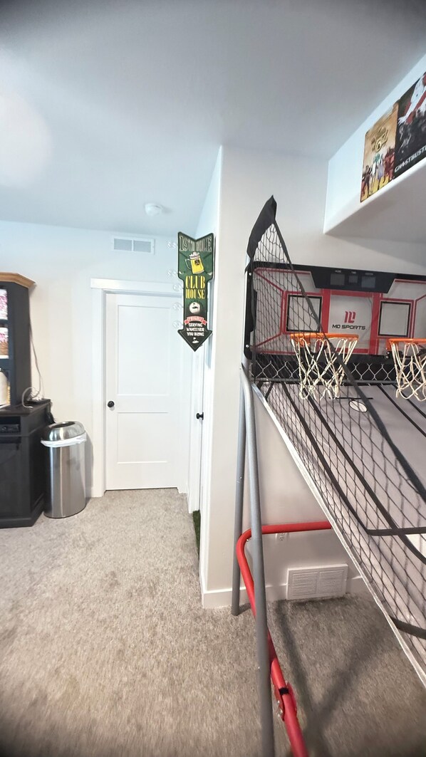 Una cama litera con aro de baloncesto, una puerta, un cesto de basura y un letrero para una casa club.