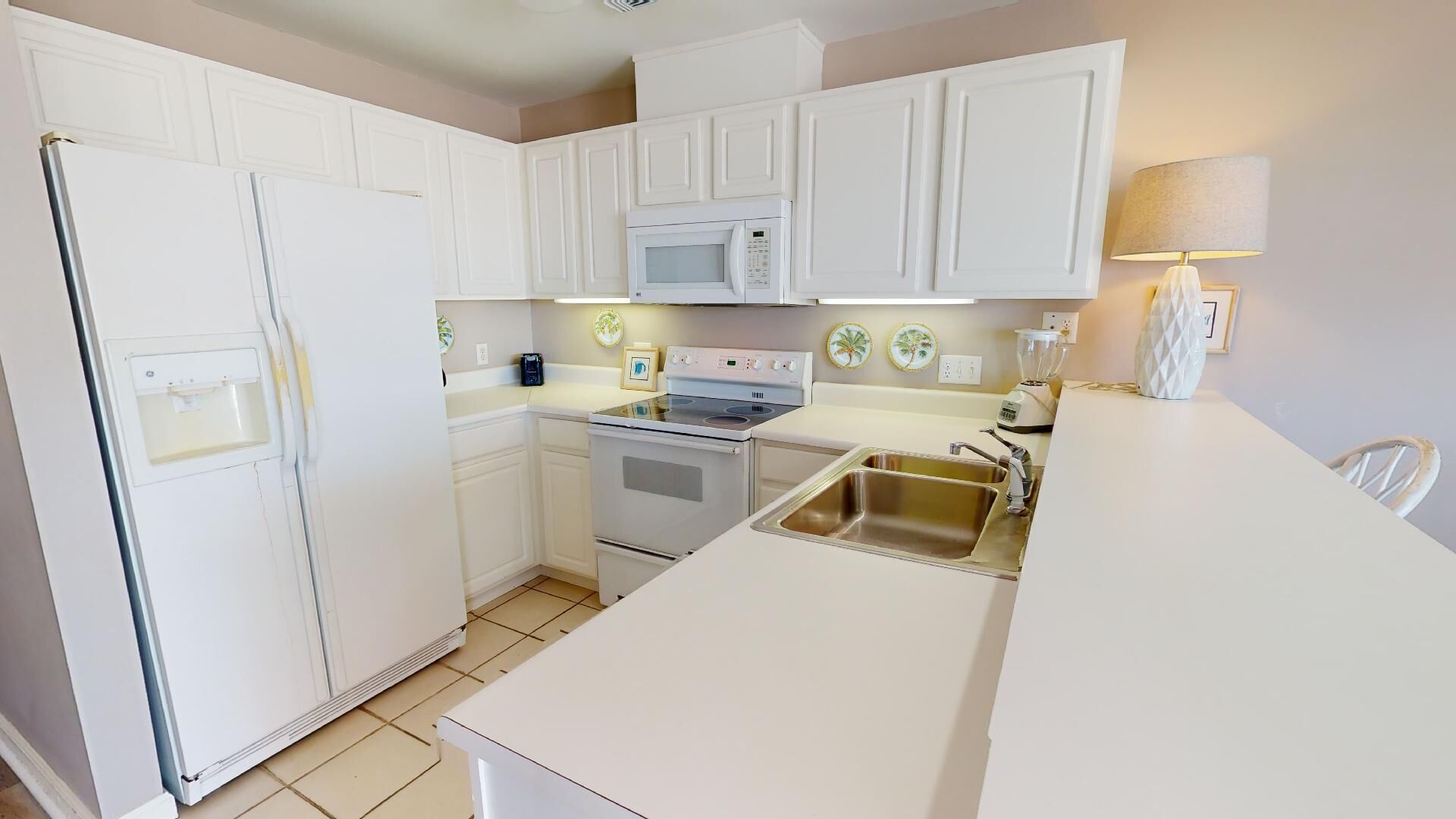 A compact kitchen with white cabinetry, a built-in microwave, an oven, a sink, and a countertop.