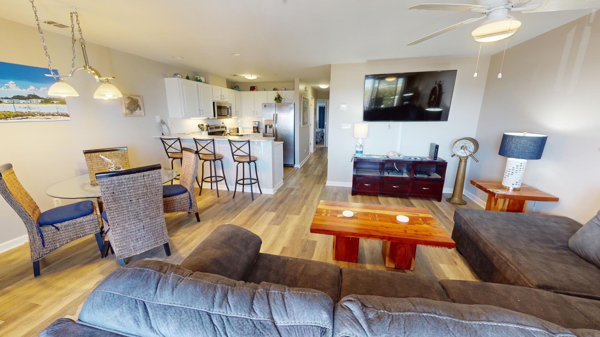 Een moderne woonkamer met een zithoek, een eettafel en een keuken op de achtergrond.