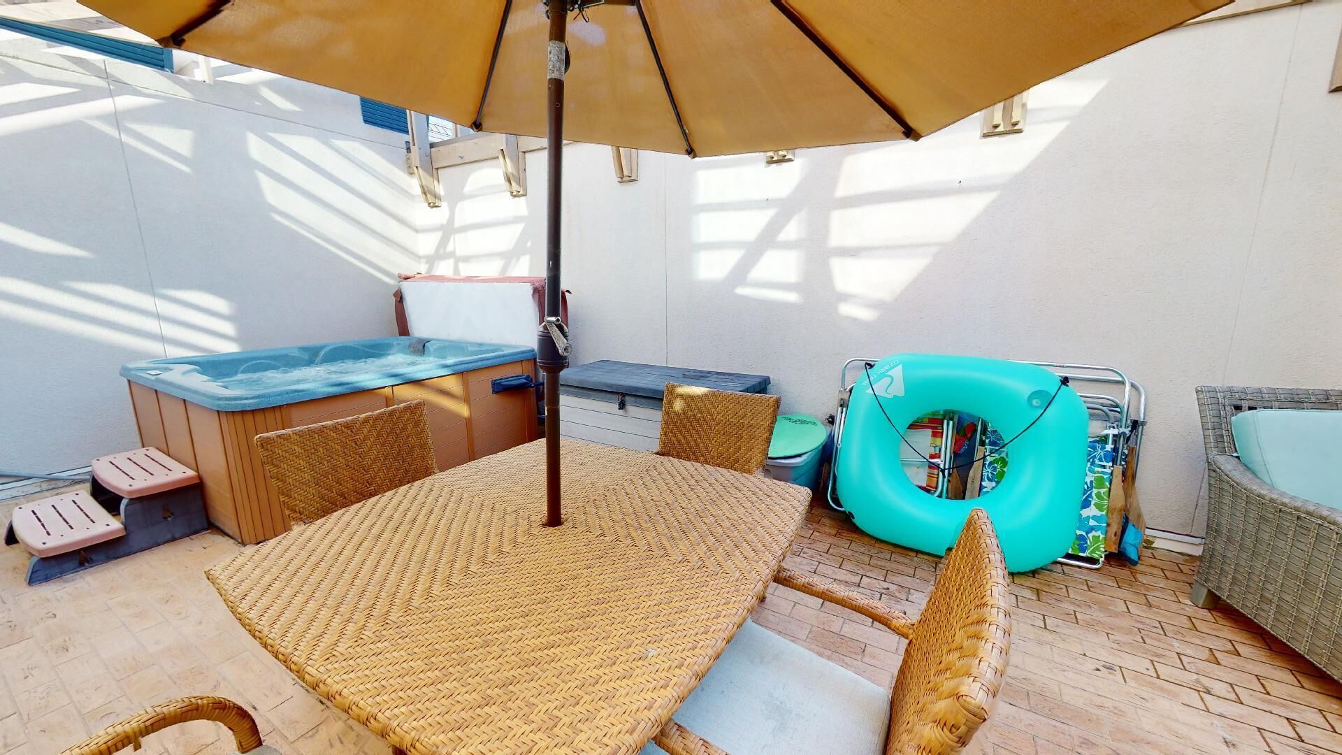 Een terras met een tafel, stoelen, een jacuzzi en een lounge stoel.