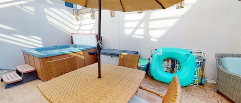 Un espace patio aménagé avec une table et des chaises, un jacuzzi et un fauteuil de relaxation.