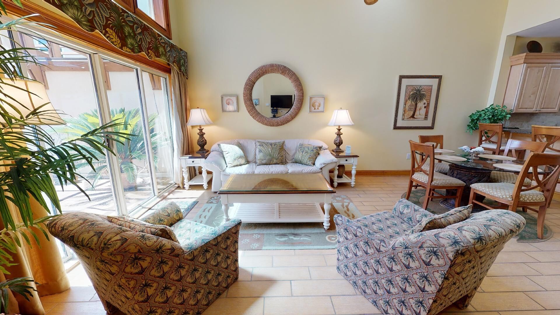 A living room with a sofa, armchairs, a coffee table, a dining table with chairs, a fireplace, and a large mirror on the wall.